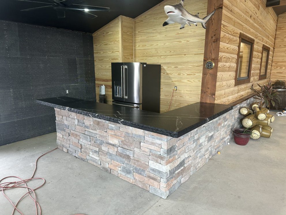 Outdoor kitchen bar with leathered granite and stacked stone — a real Precision Granite & Marble project near Lowell, AR.