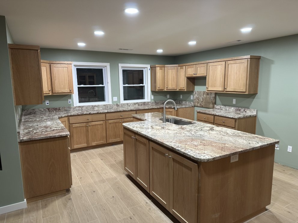 Granite countertops in warm gold and rust tones, new-construction kitchen — a real Precision Granite & Marble project.