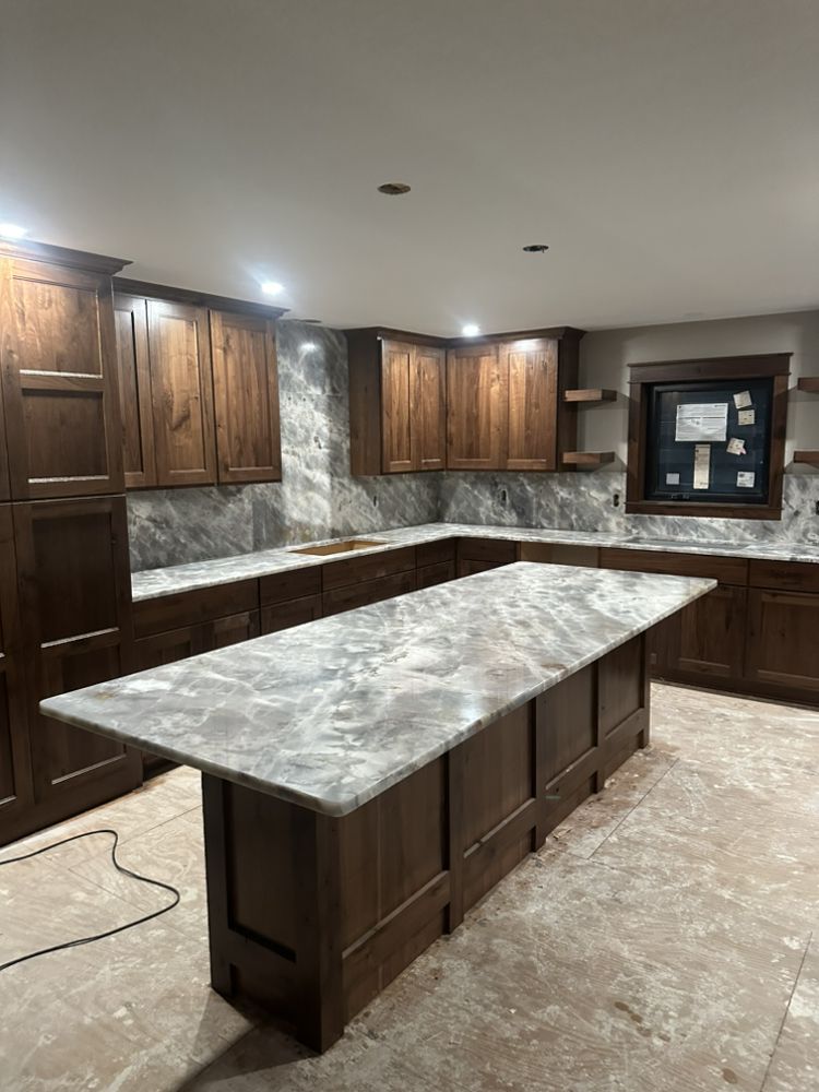 Large L-shaped kitchen with matching marble countertops and backsplash, mid-installation — a real Precision Granite & Marble project.